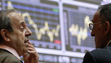 Traders talk near electronic boards at the Madrid stock exchange